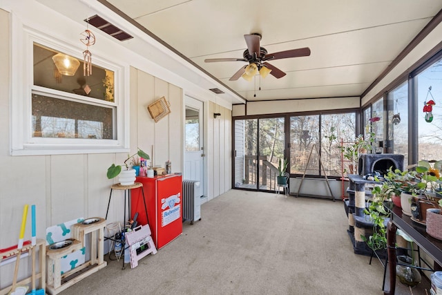 sunroom / solarium featuring radiator and ceiling fan