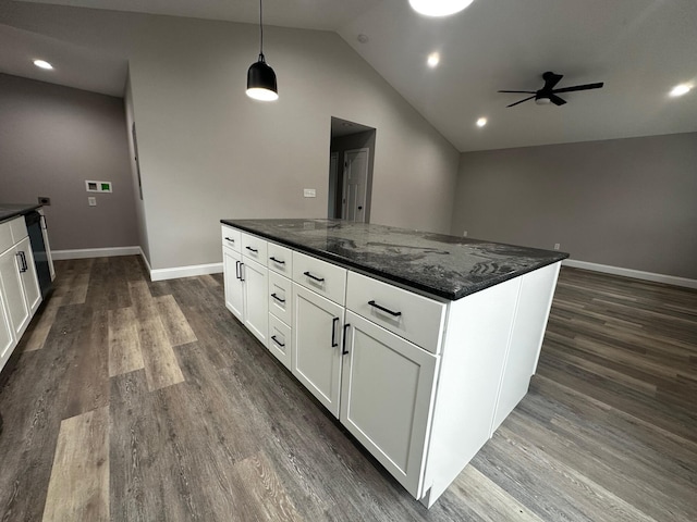 kitchen featuring dark wood-type flooring, decorative light fixtures, vaulted ceiling, dark stone countertops, and white cabinets