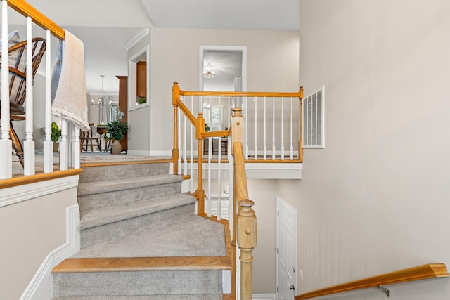 staircase with a notable chandelier