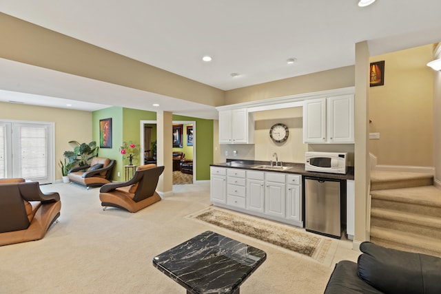 kitchen featuring white microwave, recessed lighting, a sink, white cabinets, and open floor plan