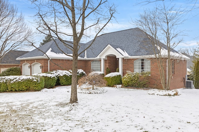 view of front of house featuring a garage, a shingled roof, central AC, and brick siding