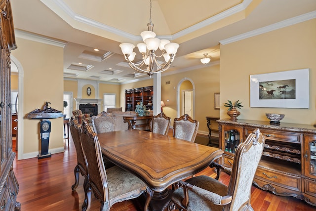 dining room with crown molding, arched walkways, dark wood-type flooring, and a glass covered fireplace