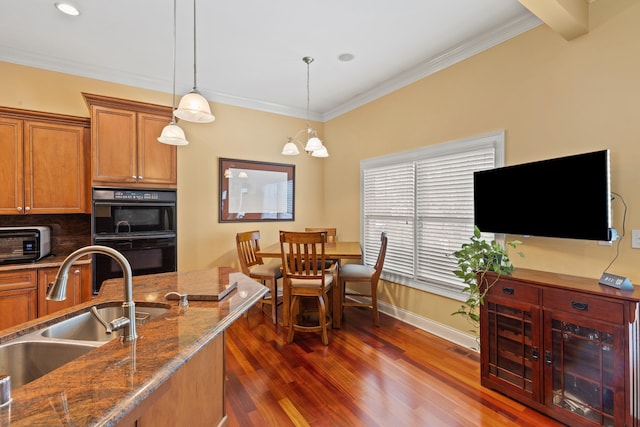 kitchen featuring backsplash, a sink, dobule oven black, and brown cabinets