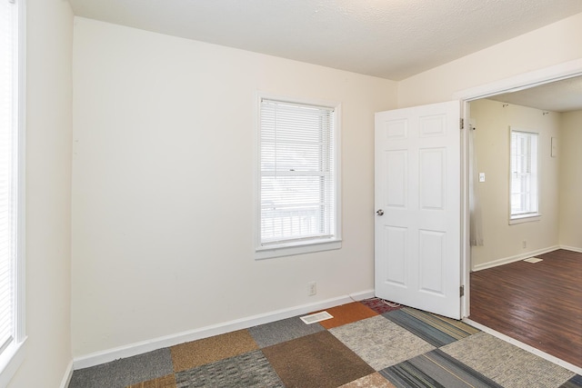 empty room with dark hardwood / wood-style floors and a textured ceiling