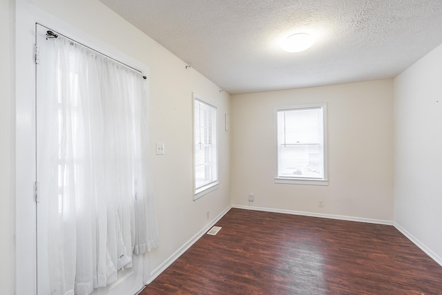 unfurnished room with dark hardwood / wood-style flooring and a textured ceiling