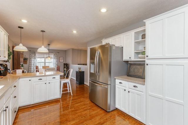 kitchen featuring white cabinetry, decorative light fixtures, and stainless steel refrigerator with ice dispenser