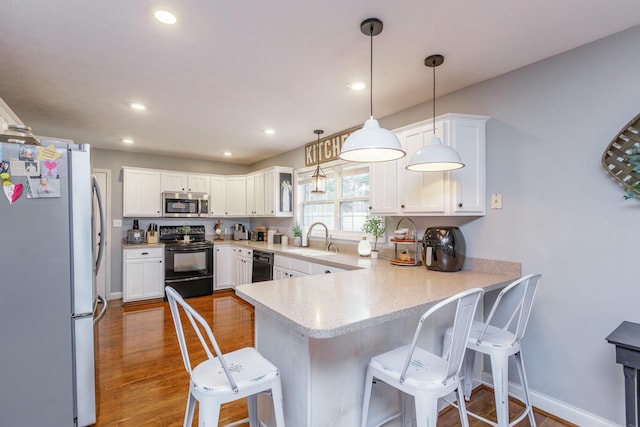 kitchen with a breakfast bar area, hanging light fixtures, stainless steel appliances, white cabinets, and kitchen peninsula