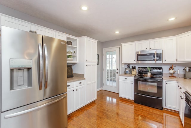 kitchen featuring white cabinetry, black appliances, and light wood-type flooring