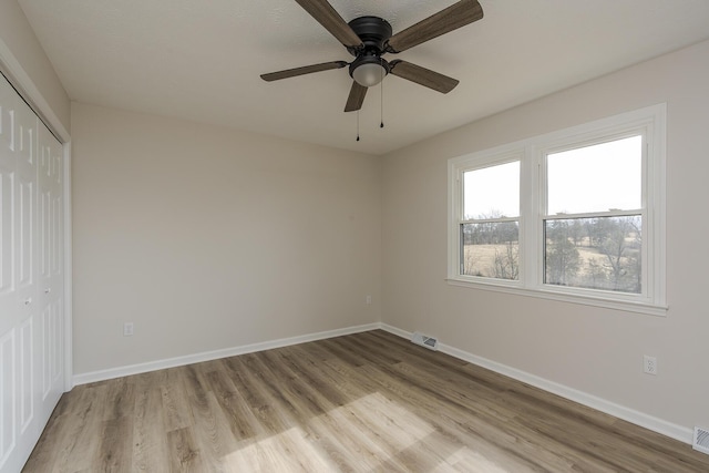 unfurnished bedroom featuring ceiling fan, light wood-type flooring, and a closet