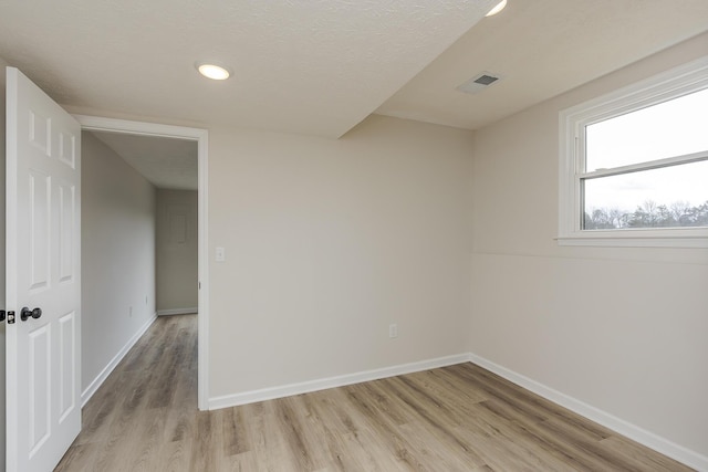 empty room with a textured ceiling and light wood-type flooring