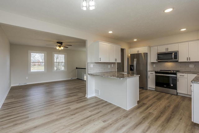 kitchen featuring white cabinetry, stainless steel appliances, kitchen peninsula, and stone counters