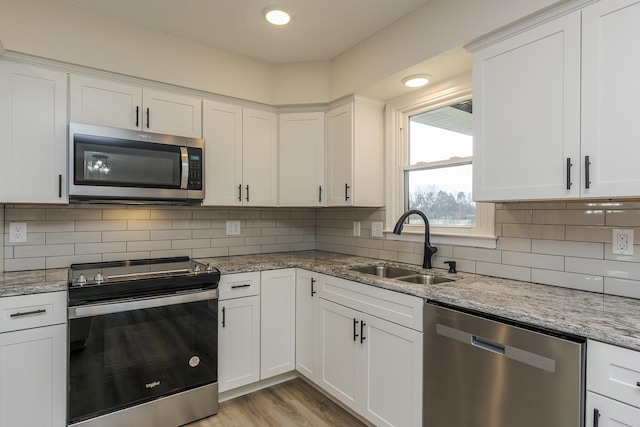 kitchen with light stone countertops, white cabinetry, and appliances with stainless steel finishes