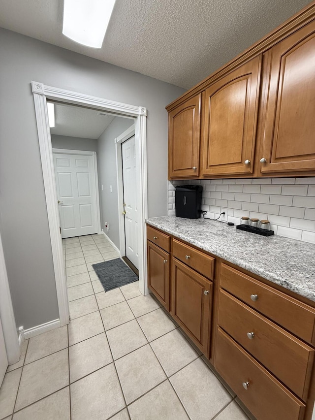 403 Chateau Pl, Bronston, KY 42518 - kitchen featuring light tile patterned floors, backsplash, a textured ceiling, and light stone counters