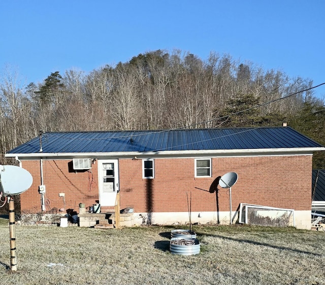 rear view of house featuring an AC wall unit and a yard