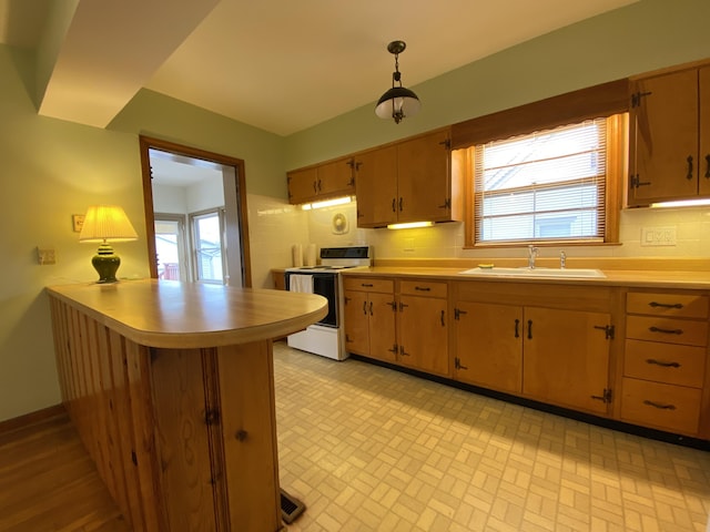 kitchen featuring sink, hanging light fixtures, kitchen peninsula, white range with electric cooktop, and decorative backsplash