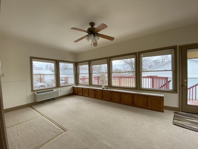 unfurnished sunroom featuring ceiling fan and a wall mounted AC