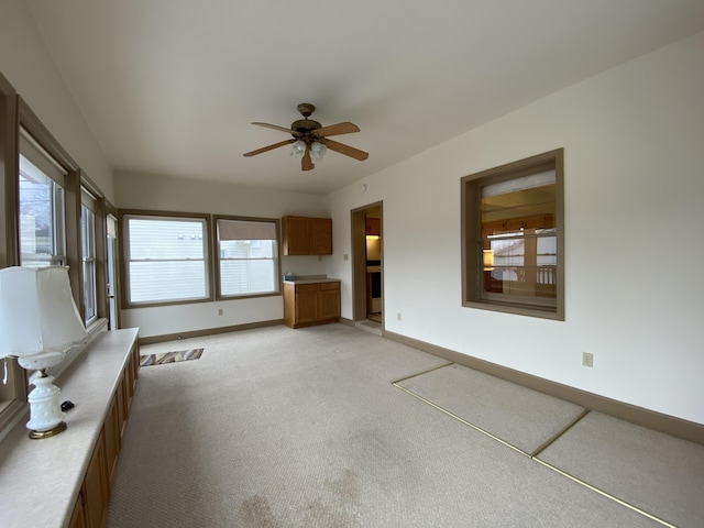 unfurnished living room featuring light colored carpet and ceiling fan