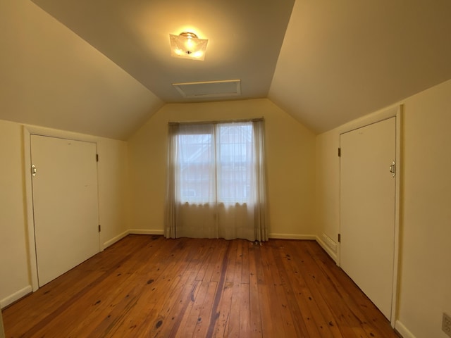 additional living space with hardwood / wood-style flooring and lofted ceiling