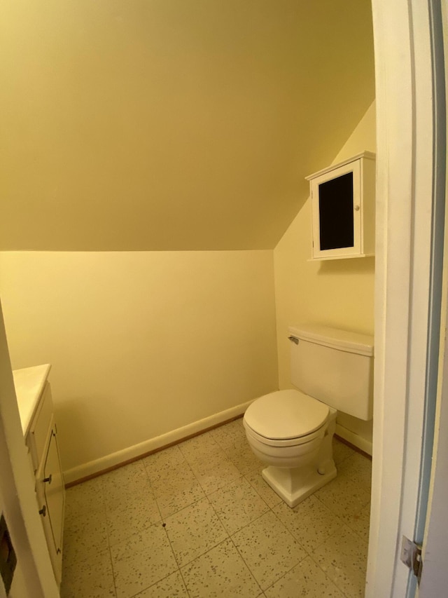 bathroom featuring vanity, toilet, and vaulted ceiling