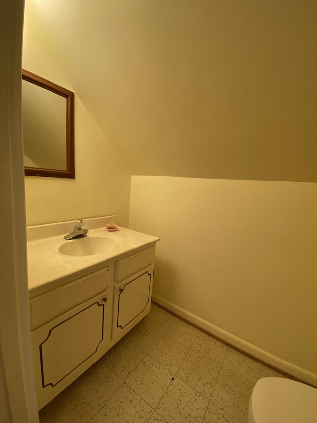 bathroom featuring vanity, lofted ceiling, and toilet