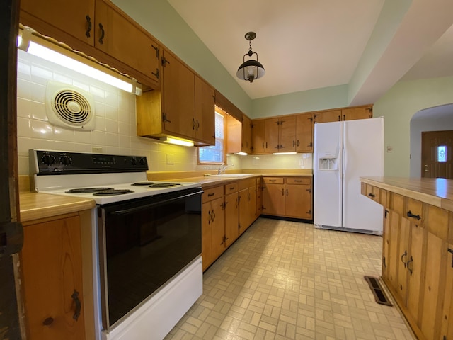 kitchen with sink, backsplash, range with electric cooktop, white fridge with ice dispenser, and decorative light fixtures