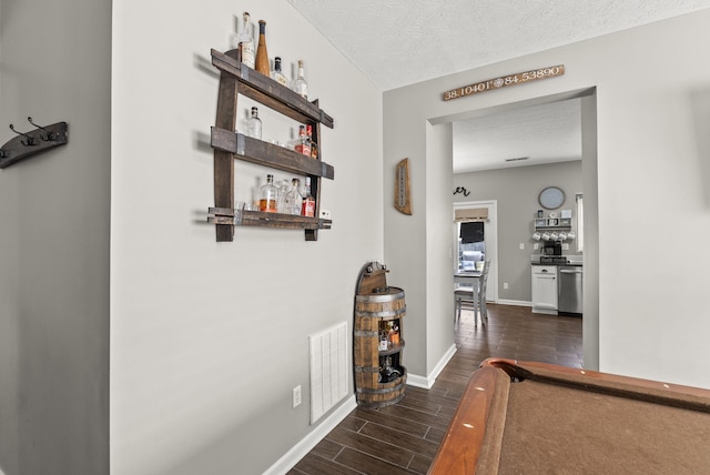 hall with dark wood-type flooring and a textured ceiling