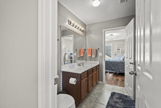 bathroom featuring tile patterned flooring, vanity, toilet, and a textured ceiling