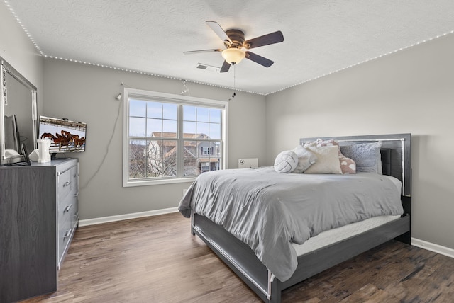 bedroom with ceiling fan, dark hardwood / wood-style floors, and a textured ceiling