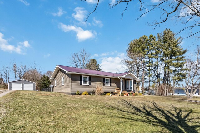 single story home with an outbuilding, a porch, a garage, and a front yard