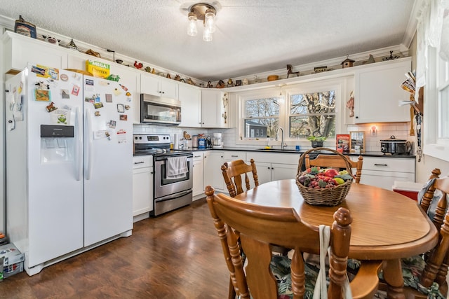 kitchen featuring sink, white cabinetry, stainless steel appliances, tasteful backsplash, and a textured ceiling