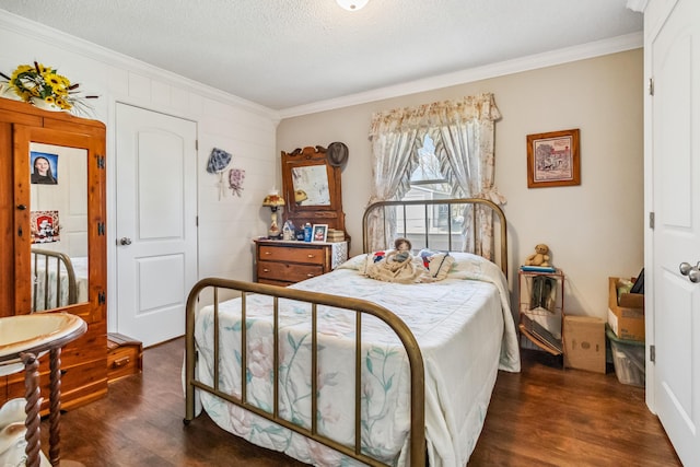 bedroom with dark wood-type flooring, ornamental molding, and a textured ceiling