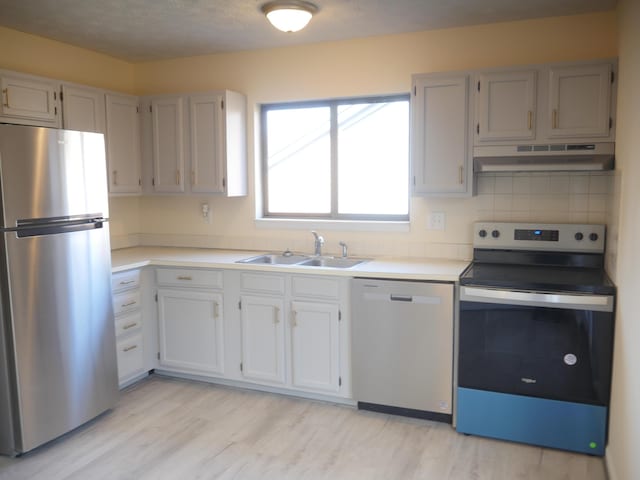 kitchen featuring stainless steel appliances, light hardwood / wood-style floors, sink, and backsplash