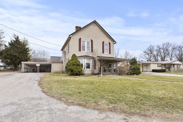 front of property featuring a carport, a garage, covered porch, and a front lawn