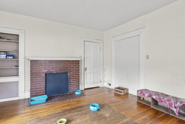 unfurnished living room with hardwood / wood-style flooring and a brick fireplace