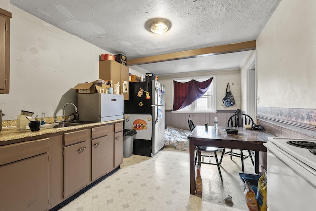 kitchen featuring sink, stainless steel fridge, white range with electric cooktop, a textured ceiling, and beamed ceiling