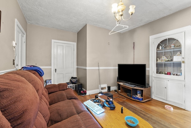 living room featuring an inviting chandelier, wood-type flooring, and a textured ceiling