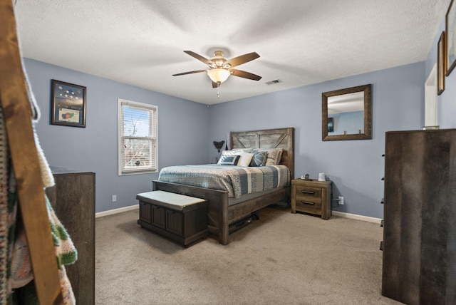 bedroom with ceiling fan, light carpet, and a textured ceiling