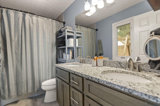 bathroom with vanity, toilet, tile patterned flooring, and a textured ceiling