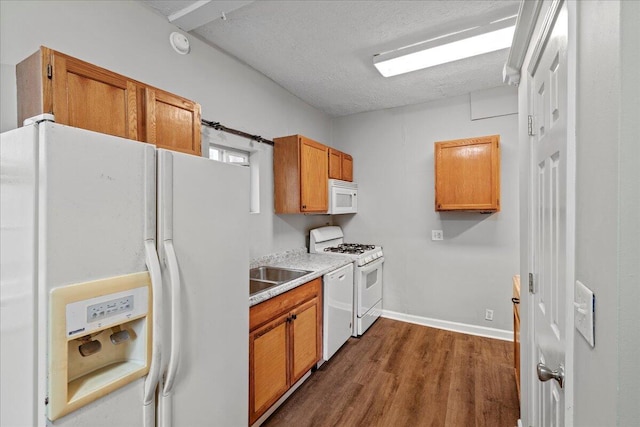 kitchen with dark hardwood / wood-style flooring, sink, a textured ceiling, and white appliances