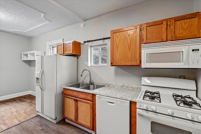 kitchen featuring white appliances, sink, light hardwood / wood-style flooring, and a textured ceiling