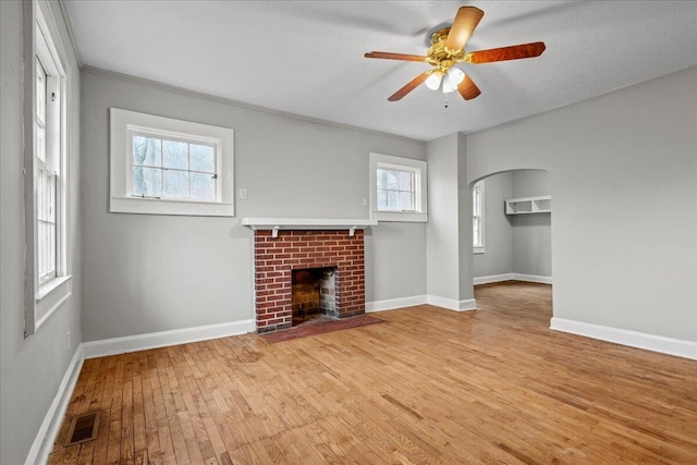 unfurnished living room featuring ceiling fan, a fireplace, and light hardwood / wood-style flooring