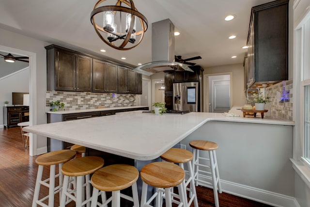 kitchen with stainless steel refrigerator with ice dispenser, island range hood, dark hardwood / wood-style flooring, and ceiling fan with notable chandelier