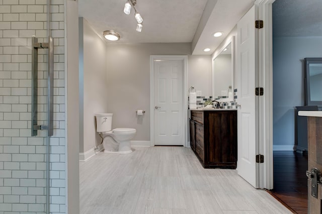 bathroom featuring walk in shower, toilet, a textured ceiling, vanity, and hardwood / wood-style flooring