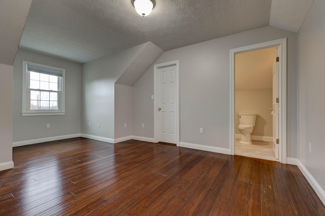 bonus room featuring lofted ceiling, dark wood-type flooring, and a textured ceiling