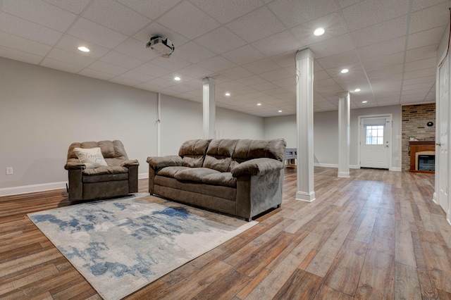 living room with a paneled ceiling, a fireplace, and light hardwood / wood-style floors