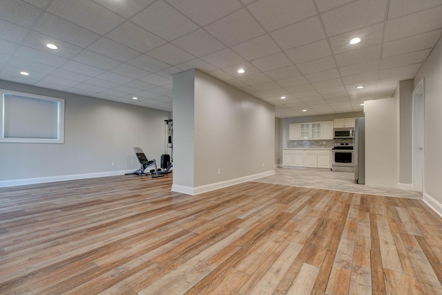 unfurnished living room with a paneled ceiling and light wood-type flooring