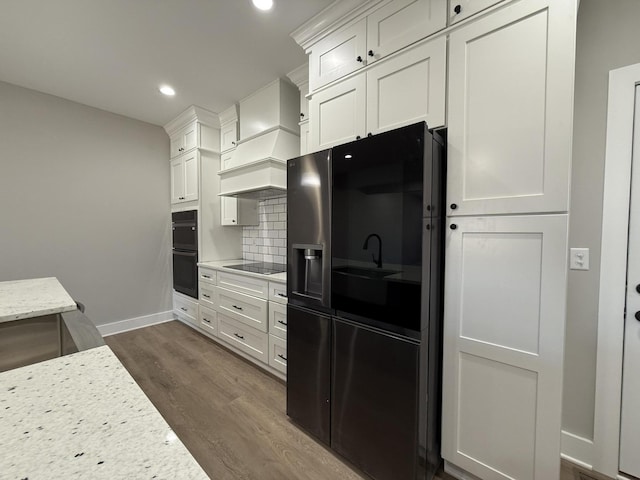 kitchen with black appliances, backsplash, light stone countertops, and white cabinets