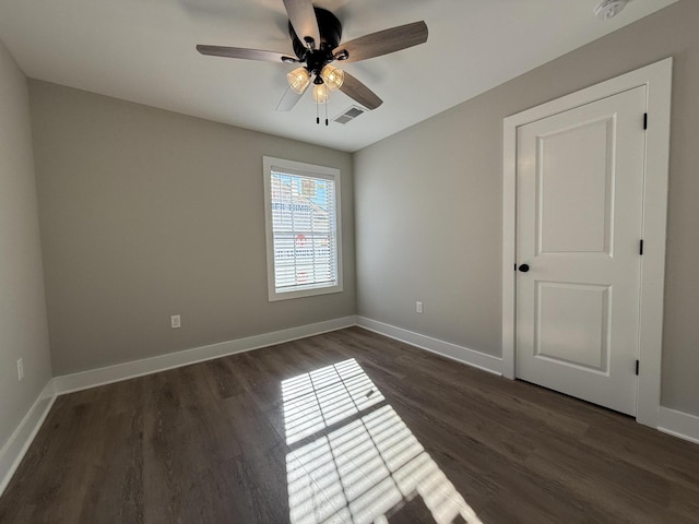 empty room with dark hardwood / wood-style floors and ceiling fan