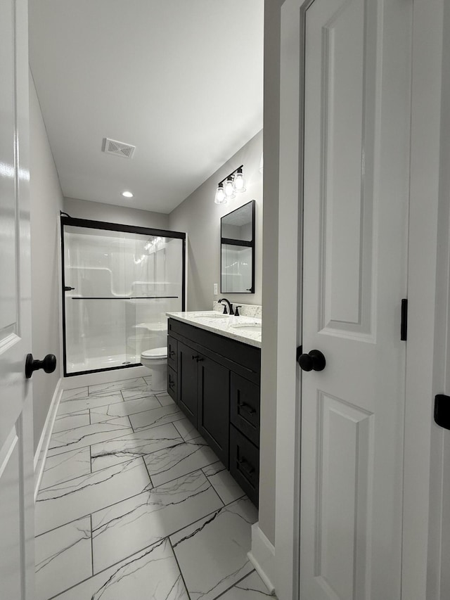 bathroom featuring vanity, a shower with shower door, and toilet