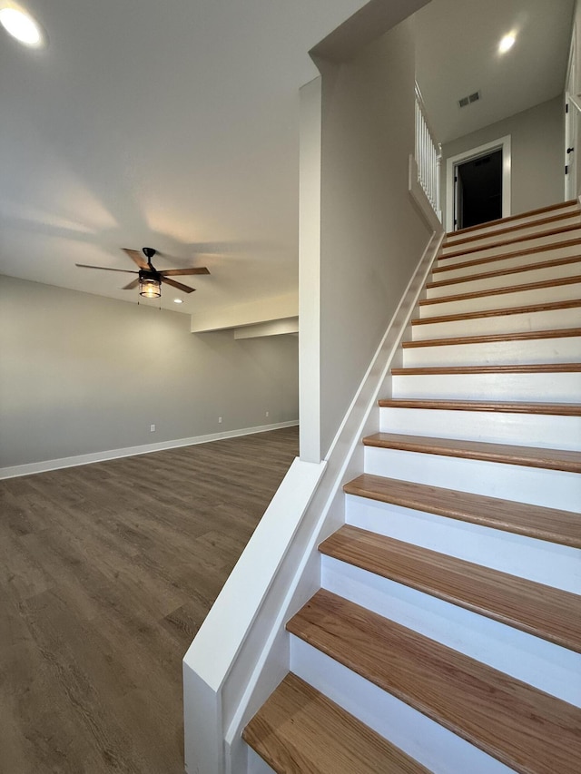 stairs featuring hardwood / wood-style flooring and ceiling fan